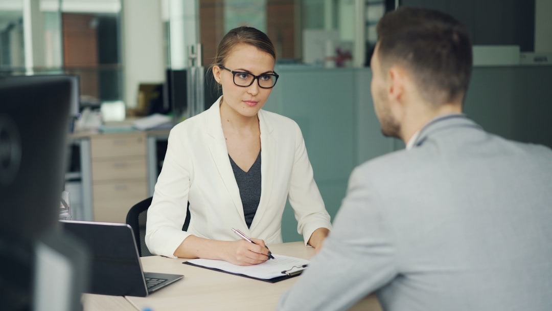 Woman in glasses writes on clipboard during business meeting.